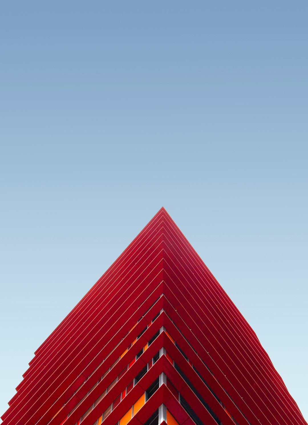 Bold red abstract architectural sculpture against a clear sky